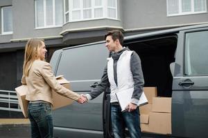 courier shaking hands near the van, woman receives box photo