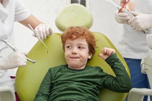 Little cute boy sitting in chair at dentist photo