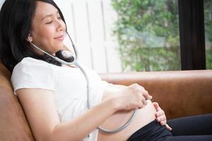 Pregnant woman using stethoscope