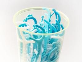 Blue dental floss sticks in plastic cup photo