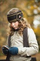 Chica adolescente enviando mensajes de texto con celular en un día de otoño foto