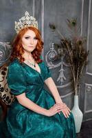 reina, persona real con corona, cabello rojo y vestido verde foto