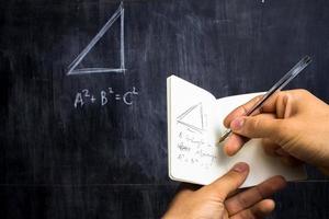 Man taking notes of math theorem on blackboard photo