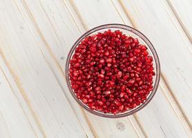 juicy pomegranate seeds in a glass bowl photo