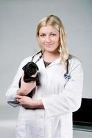 Young female blonde veterinarian holding a cute pug puppy photo