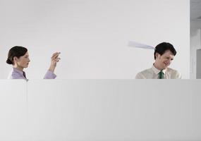 mujer lanzando aviones de papel a colega masculino foto