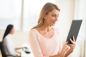 Happy Businesswoman Looking At Touchpad In Office photo