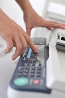 Hands of businessperson operating a fax machine photo