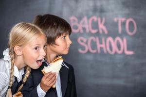Foto divertida de niño y niña de escuela con sándwiches