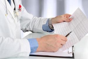 healthcare and medicine concept - doctor with clipboard analizing cardiogram