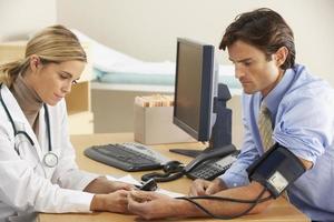 Un médico que habla con un paciente y le toma la presión arterial. foto