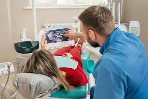 dentista mostrando al paciente su imagen de dientes de rayos x foto