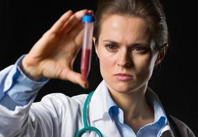 mujer médico mirando el tubo de ensayo con sangre foto