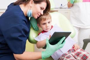 Modern dentist use wireless tablet with kid patient photo