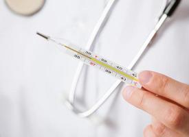 Doctor's hand holding thermometer photo