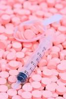 Jeringa y cuchara en pastillas de color rosa para el concepto de salud foto