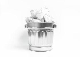 Stainless waste basket filled with crumpled paper on white backg photo