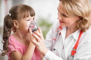 médico pediatra haciendo inhalación a paciente niño foto
