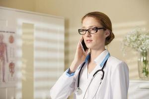 Young beautiful woman doctor with phone