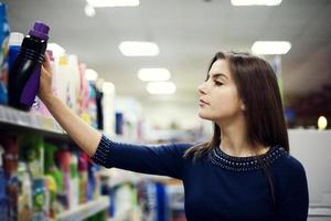 Woman choosing detergent in supermarket