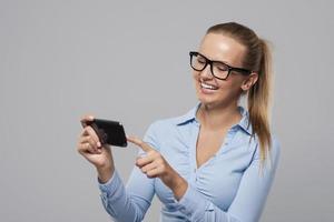 Smiling woman with glasses using mobile phone photo