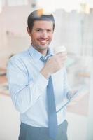 Empresario sonriente con tableta y vaso desechable foto