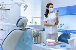 Dentist in mask holding green apple. photo