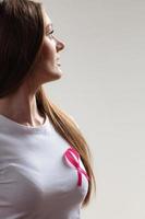 mujer en camiseta con cinta de cáncer rosa sobre gris