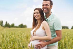 Pregnant woman with her man in the summer field photo