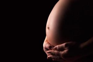 silueta de mujer embarazada sobre fondo negro foto