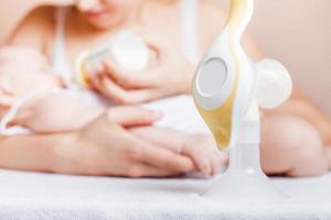 Manual breast pump and mother feeding a newborn baby