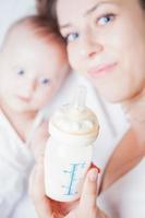 madre y bebé sosteniendo un biberón con leche materna foto