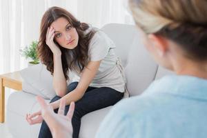 Worried woman sitting and looking at camera during therapy photo