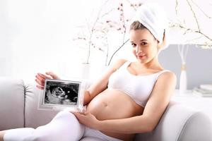 Pregnant woman showing ultrasound baby photo