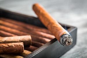 cigarro encendido con humo en humidor de madera