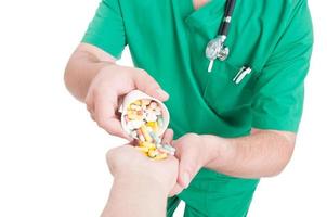 Doctor, medic or pharmacist pouring pills in patient hand photo