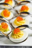 huevos rellenos con caviar rojo en una cuchara foto