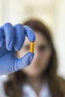 woman holding yellow pill capsules photo