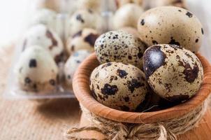 raw quail eggs in a wooden bowl on burlap background photo