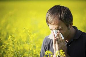 Man blowing his nose in canola field photo
