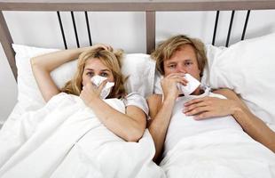 Retrato de pareja sufriendo de frío acostado en la cama foto