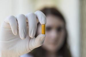 mujer sosteniendo cápsulas de píldora amarilla