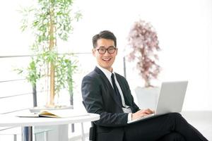 Young asian businessman using tablet, mobile phone in the office photo