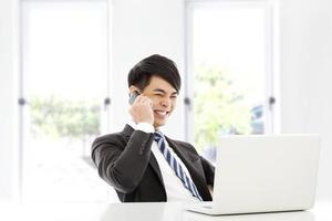 joven hombre de negocios hablando alegremente por teléfono inteligente en la oficina