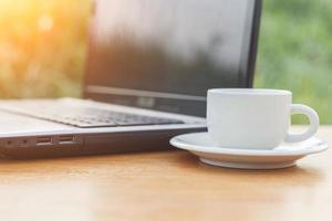 taza de café y laptop en la mesa foto