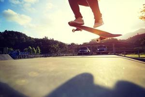 skateboarder legs doing a trick ollie at skatepark photo