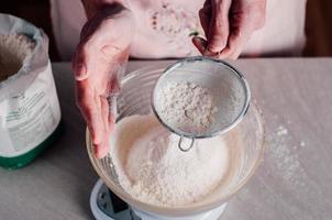 Man sifting flour for pizza dough photo