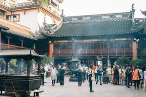 Adoradores y turistas en el templo budista en Shangai foto