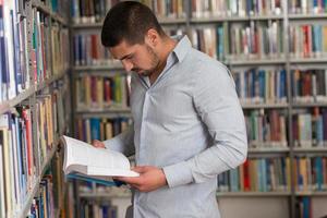 feliz estudiante masculino con libro en la biblioteca foto