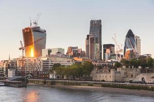 Tower of London and Modern Skyscrapers on Background at Sunset photo
